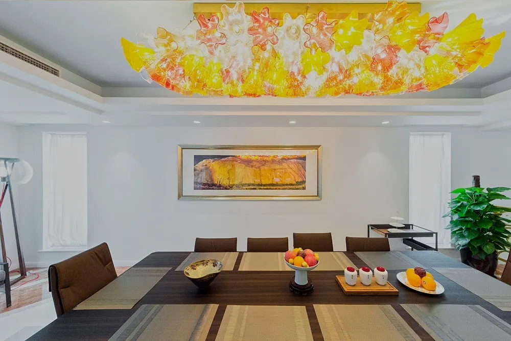 Dining room with a long table beneath a yellow and orange glass ceiling light, 4 Seasons Villa