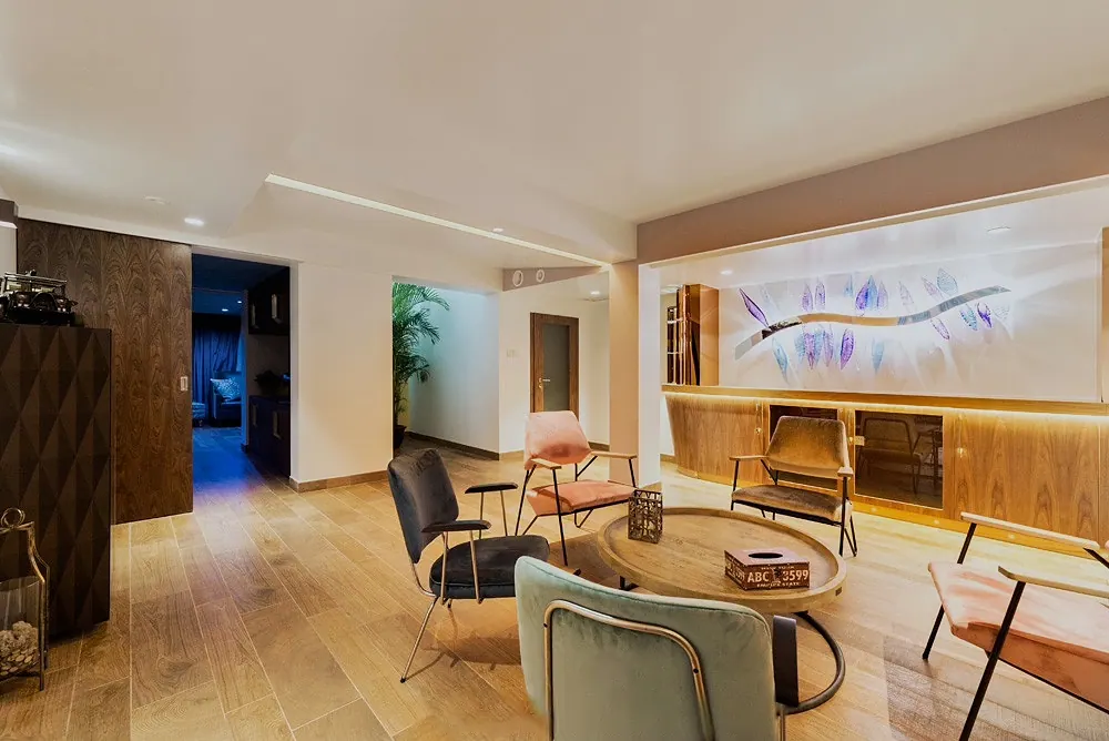 Lounge with armchairs, a round wooden table and a backlit wall artwork, 4 Seasons Villa