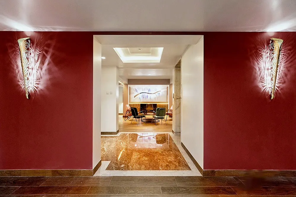 Deep red corridor with two cone-shaped wall lights framing a view into a lounge, 4 Seasons Villa