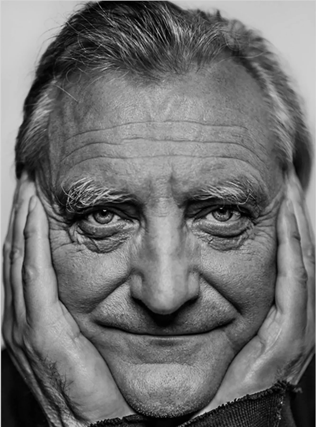 Black-and-white portrait of Bořek Šípek smiling with his hands framing his face