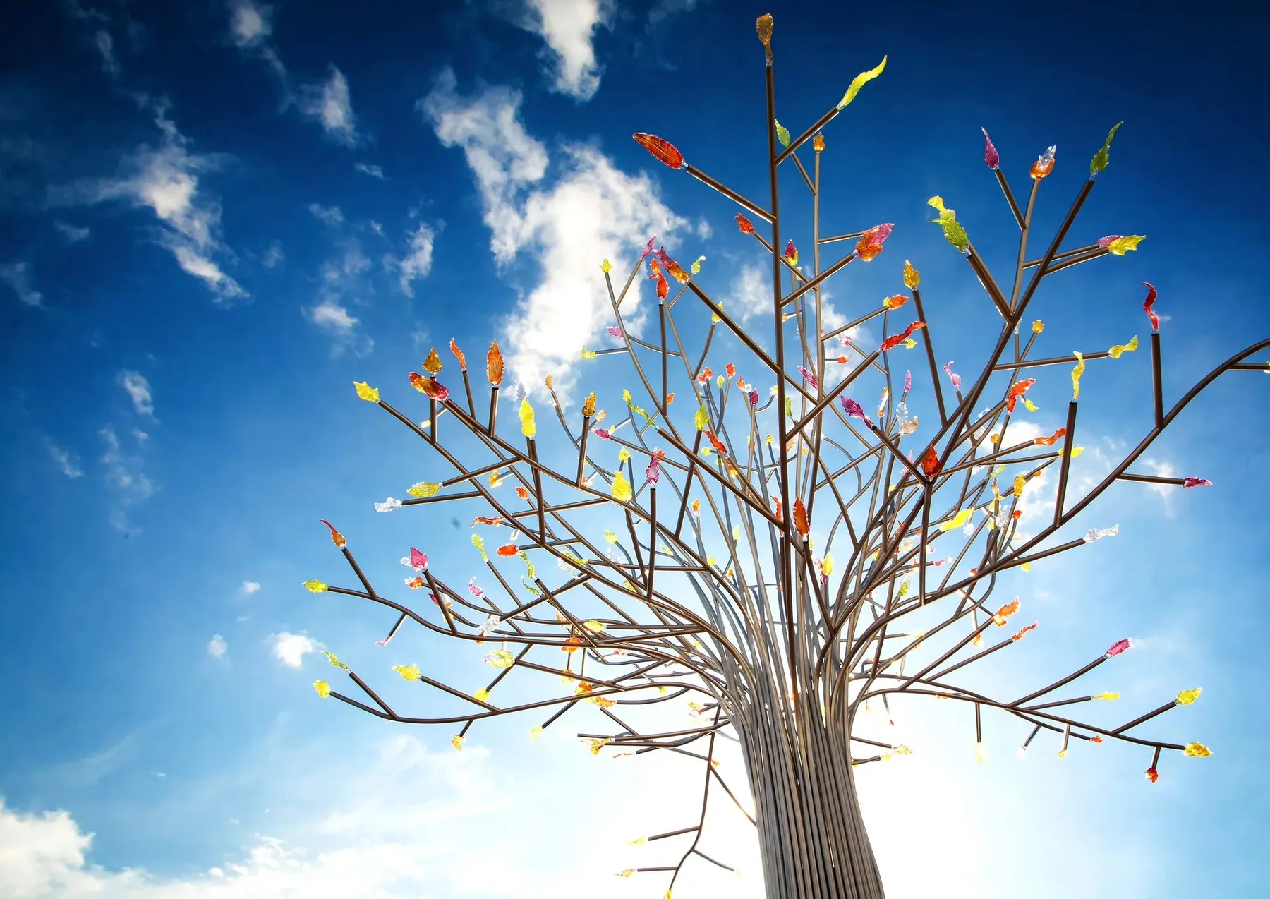 View up into branches tipped with coloured crystal leaves against a blue sky, Crystal tree