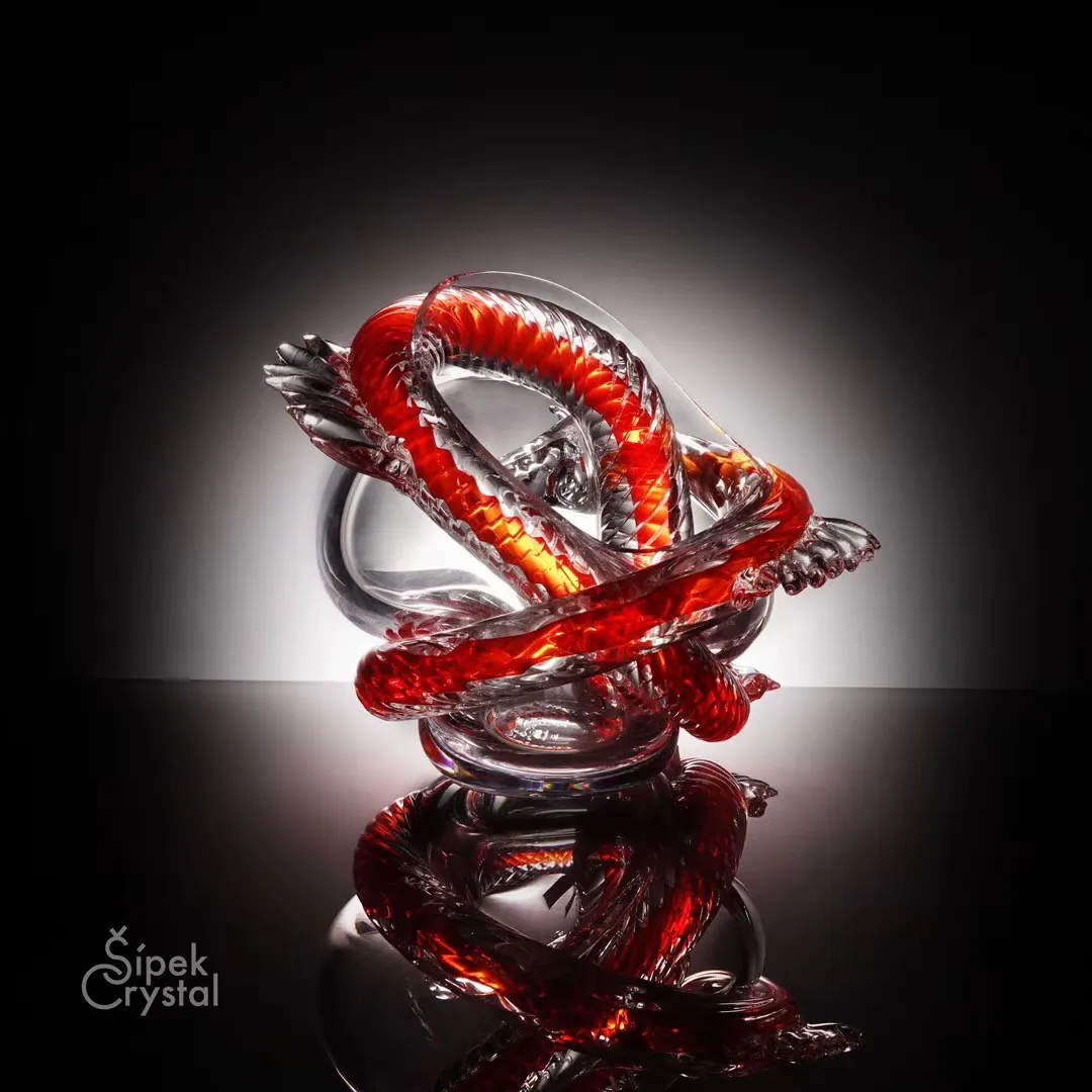 Knotted red and clear crystal sculpture glowing against a dark background, Crystal art pieces