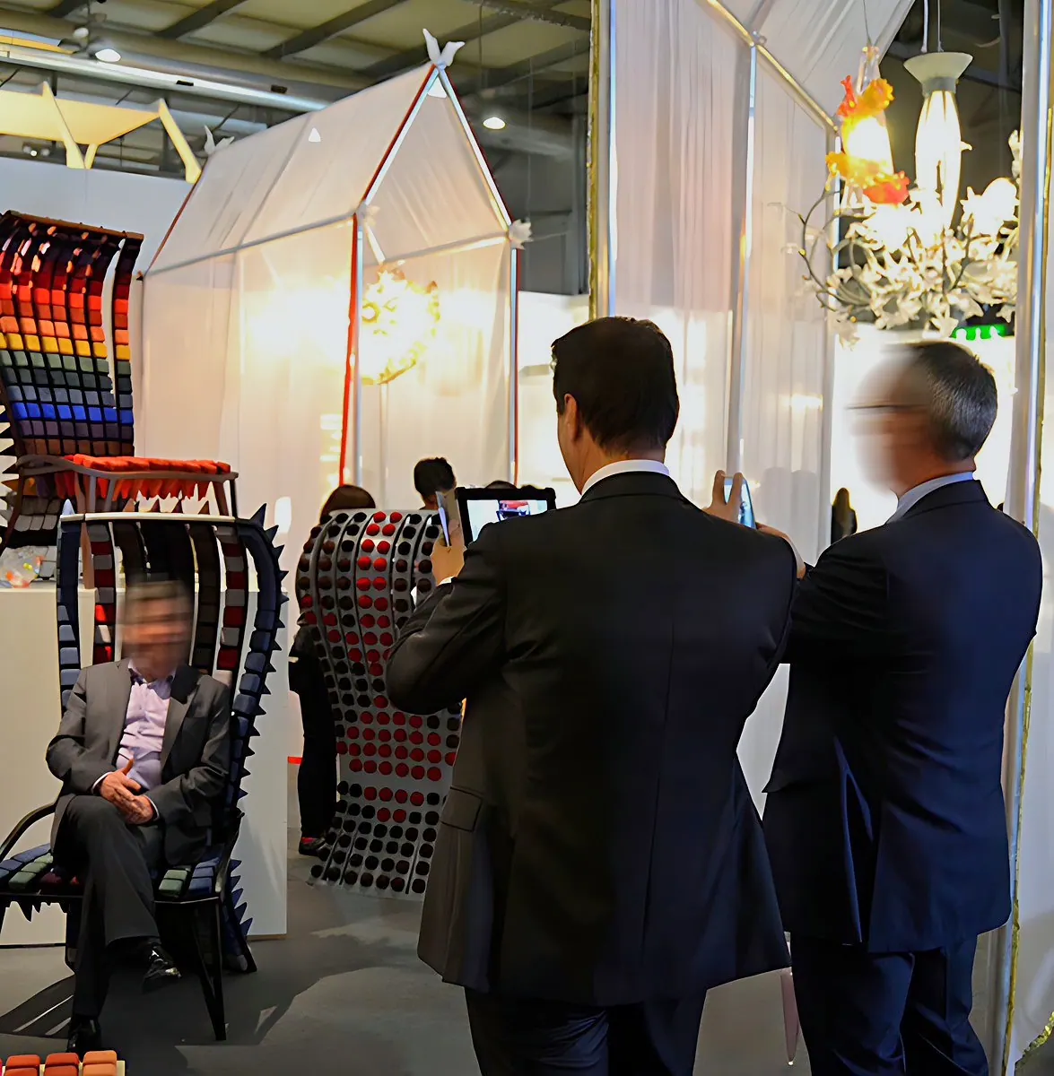 Visitors at a trade fair stand with colourful Morphit chairs, a man seated in one