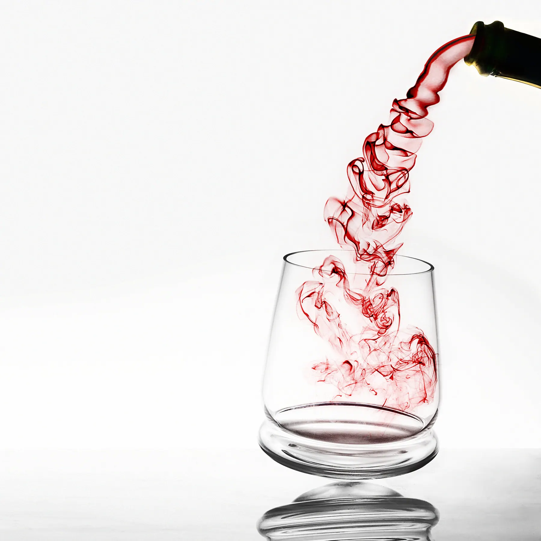 Red wine pouring from a bottle into a clear tilted glass, Tipsy glass collection